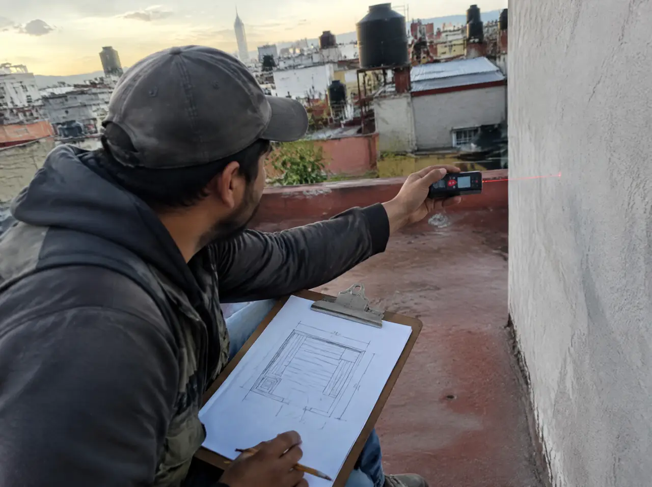 Topógrafo midiendo una azotea con láser y croquis de sauna en una tabla