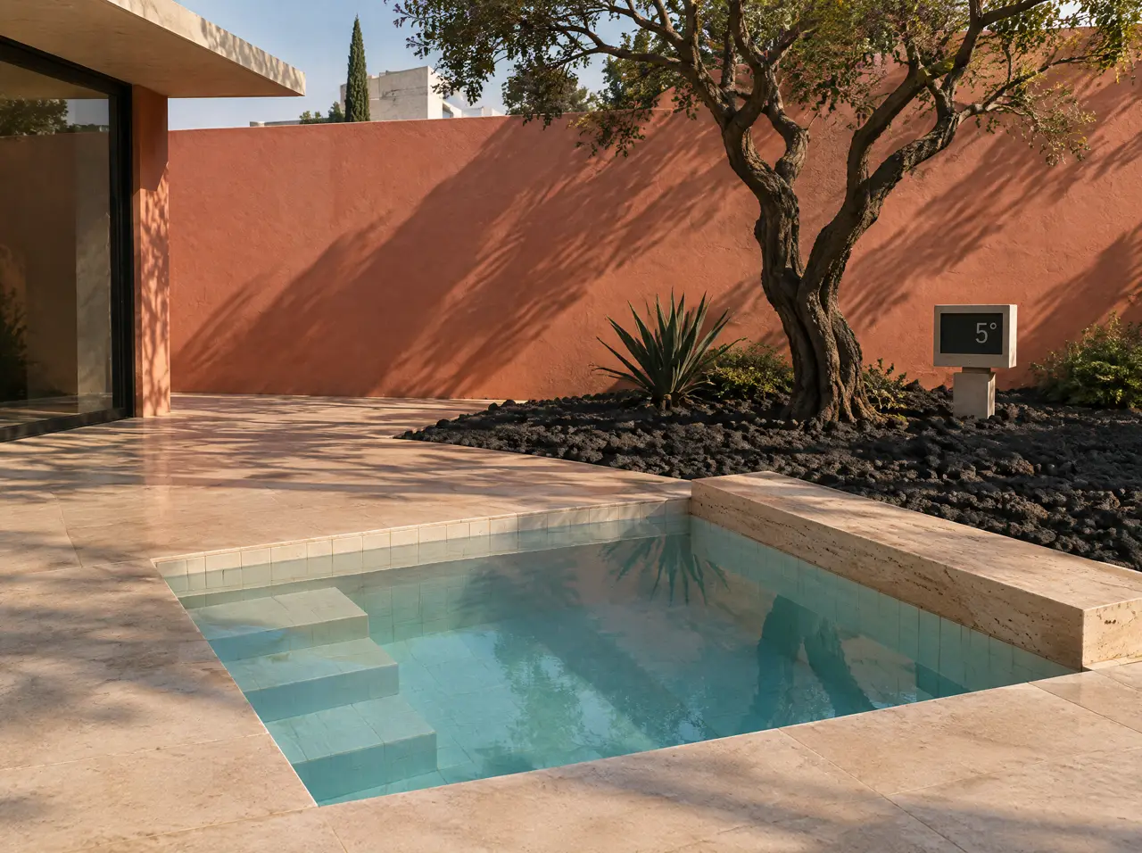 Piscina fría cuadrada con borde de travertino en un patio de lava con muro rosa