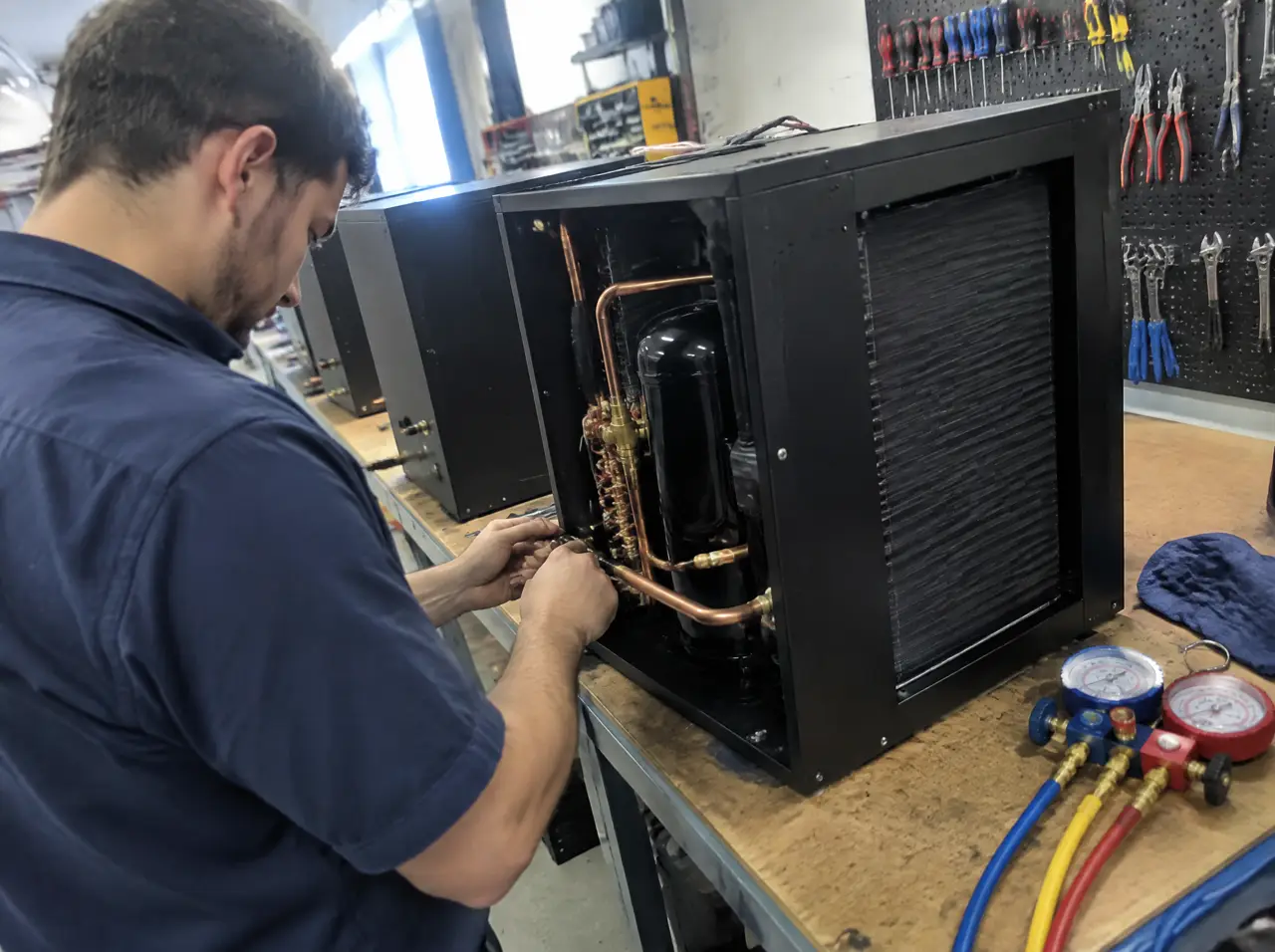 Técnico de refrigeración conectando tuberías de cobre dentro de la caja negra de un enfriador